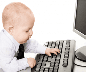 baby in shirt and tie sitting at computer keyboard to emphasise the importance of being business-like when feeding our babies